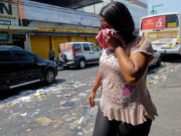 Mulher protege o nariz do cheiro forte de lixo nas ruas do centro da cidade de Caxias